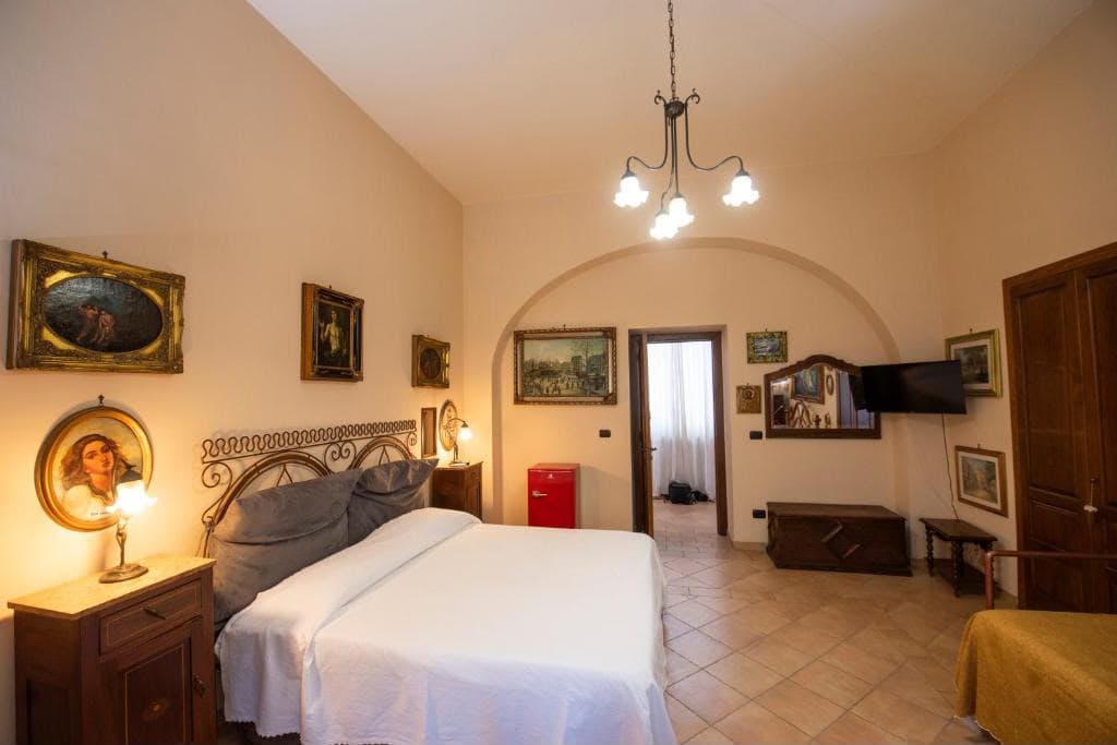 Camera con letto matrimoniale, lampadario e soffitto voltato